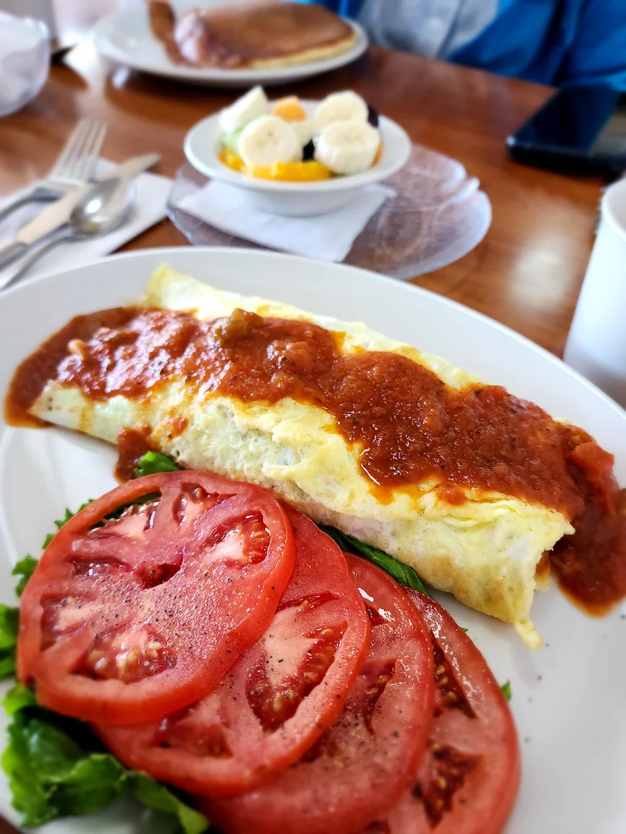 Spanish Omelet with a Side of Fresh Tomatoes and Bowl of Fruit Salad