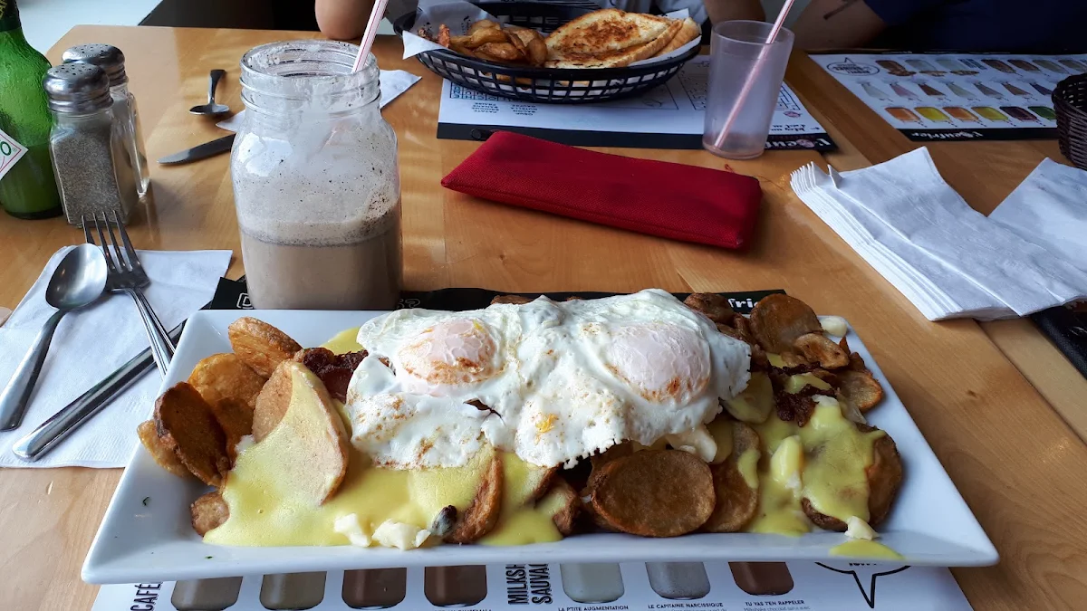 Poutine with Hollandaise Sauce Cheese Curds Sausage and Bacon and Two Eggs Easy over on Top