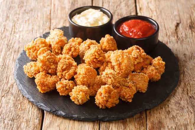 Popcorn chicken with sweet chili sauce on side.